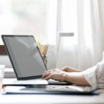 Cropped shot of businesswoman using laptop computer while sitting at office desk.